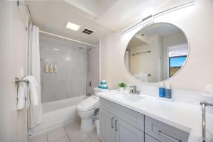 a bathroom with a sink and a toilet and a mirror at 34th floor lanai with Diamond Head views, pool & hot tub access in Honolulu
