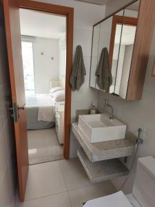 ein Badezimmer mit Waschbecken und Spiegel und einem Bett in der Unterkunft Alto Padrão, Vista Mar, Varanda Gourmet, Nascente Compartilhar SalvarHigh Standard, Sea View, Gourmet Balcony, East-facing in Guarapari