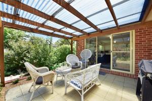 黑荒地4BR 2BA Cozy Blackheath Cottage with Firepit & Pool Table的庭院中设有1个带椅子和桌子的温室