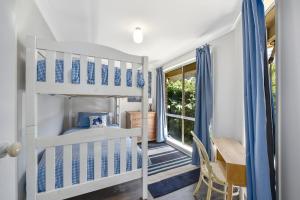 黑荒地4BR 2BA Cozy Blackheath Cottage with Firepit & Pool Table的一间卧室配有一张双层床、一张桌子和一张书桌。