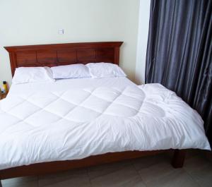 a bed with a wooden headboard and white sheets at 2 Bedroom Suite with Sitting Area in Kigali