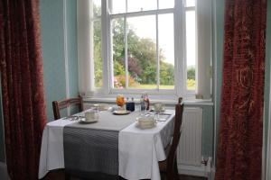 a table with a white table cloth and a window at Trevanger Farm Bed and Breakfast in Wadebridge