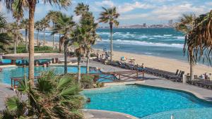 a swimming pool next to a beach with palm trees at Sonoran Sun in Campo del Medio