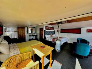 プーノにあるTiticaca uros floating lodgeのベッド2台とテーブルとソファのある寝室