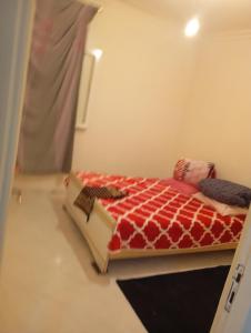 a bedroom with a bed with a red and white comforter at Parc jardin badr in Tangier