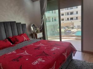 ブズニカにあるSpécial CAN 2025,louer votre appt sur Bouznika entre Rabat & Casaのベッドルーム1室(赤いベッド1台、大きな窓付)