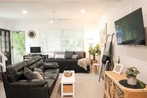 a living room with a leather couch and a tv at Whitsunday Pandanus-Stylish 2 bedroom townhouse in quiet location in Cannonvale