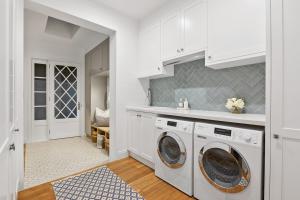 une cuisine avec des armoires blanches et une laveuse et une sécheuse dans l'établissement Coastal Luxe - Hampton inspired, à Kingscliff