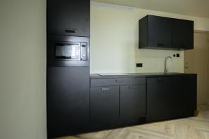 eine Küche mit schwarzen Schränken und einer Mikrowelle in der Unterkunft Aki Banda Suites in Willemstad