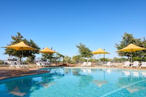 a swimming pool with yellow umbrellas and chairs at RAC Exmouth Cape Holiday Park in Exmouth