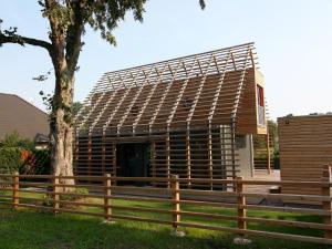 a wooden house with a tree and a fence at Chalet in Wendorf, cleaning included in Wendorf