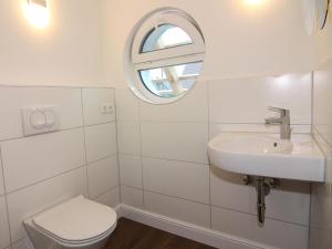 a white bathroom with a toilet and a sink at Chalet in Wendorf, cleaning included in Wendorf