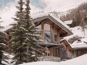 una cabaña de madera en la nieve con un árbol de Navidad en Chalet montagnard intime avec hammam à Val d'Isère - FR-1-844-19, en Val dʼIsère