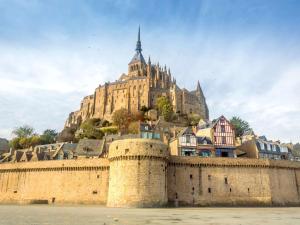 a castle on a hill behind a wall and buildings at Appartement en bord de mer, 1 chambre, 4 couchages, parking privé - FR-1-361-570 in Jullouville-les-Pins +7 photos