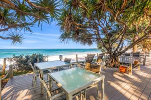 a table and chairs on a wooden deck next to the beach at Nautilus Resort Apartment 162 Solitary Islands Way 8 in Sapphire Beach