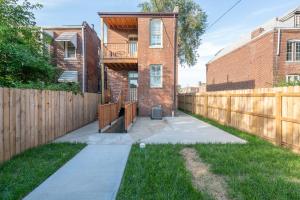 un patio trasero con una valla de madera y un edificio de ladrillo en Parkside Comfort | JZ Vacation Rentals, en Tower Grove