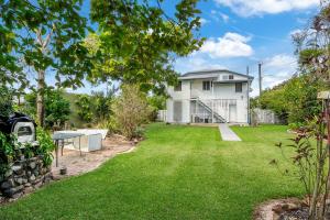 a backyard with a white house and a lawn at Charming Queenslander Retreat in Mundingburra in Rosslea