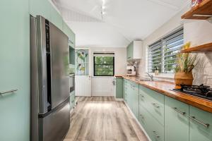 a kitchen with green cabinets and a stainless steel refrigerator at Charming Queenslander Retreat in Mundingburra in Rosslea