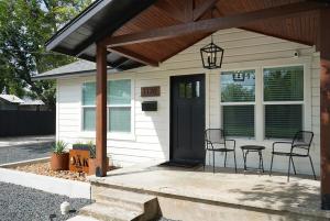 ein kleines weißes Haus mit einer schwarzen Tür und Stühlen in der Unterkunft Oak and Agave House - Downtown New Braunfels Retreat in New Braunfels