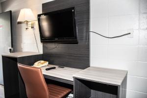 a room with a desk with a television and a telephone at Budget Inn in Carthage