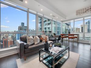 Una sala de estar con un sofá y grandes ventanales. en Nobu Suites - Toronto's Entertainment District, en Toronto