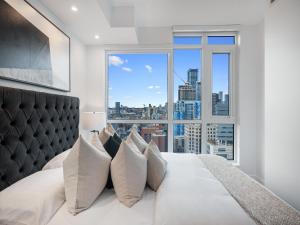 Un dormitorio con una cama grande con una ventana grande. en Nobu Suites - Toronto's Entertainment District, en Toronto