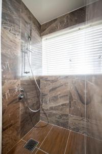 a bathroom with a shower with a stone wall at WITH SEA Nakama in Onna