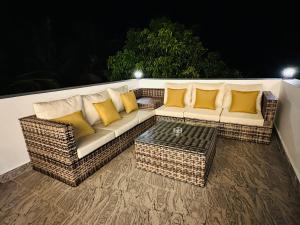 a wicker couch with yellow pillows on a patio at Bamboo Breeze Jaffna in Jaffna