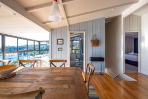 Un comedor con una gran mesa y sillas de madera. en Clifftop Sanctuary - Stay Waiheke, en Oneroa