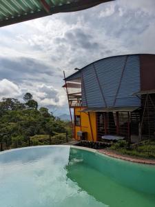 ein Haus mit einem Swimmingpool vor einem Gebäude in der Unterkunft Alojamiento el Mirador in Tapantí