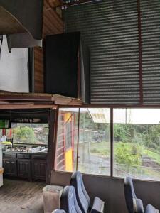 ein Restaurant mit Stühlen in einem Raum mit Fenstern in der Unterkunft Alojamiento el Mirador in Tapantí