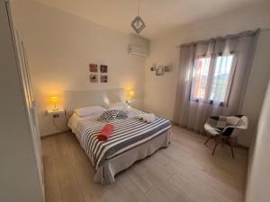 a bedroom with a bed and a chair and a window at Casa Le Cicale in Porto Istana