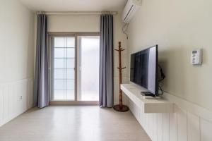 Una sala de estar con televisión y una ventana. en Jeju Albam Oreum House Pension, en Jeju 26 fotos más