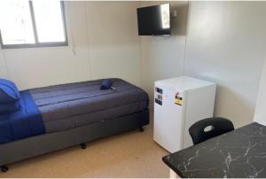 a small room with a bed and a small refrigerator at Discovery Parks Workstay Villages -Tindal Village in Katherine