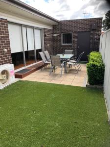 een patio met een tafel, stoelen en gras bij Lbarza Stylish 3BR Central Serviced Apartment in Shepparton