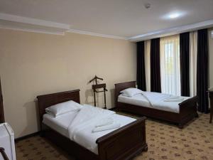 a hotel room with two beds and a window at Hotel YOSHLIK in Navoi