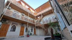 a building with stairs and a tree in a courtyard at Naqshband Terrace in Bukhara