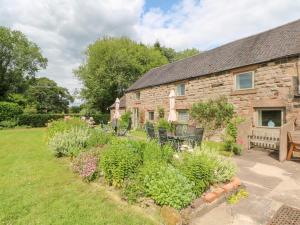 a stone house with a garden in front of it at Lee House Cottage in Cheddleton