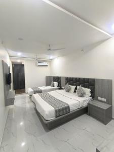 a bedroom with two beds and a television in it at Hotel RD in Kadi
