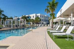 een zwembad met witte ligstoelen naast een gebouw bij Daytona 2BR w Parking – Family Pet Friendly in Daytona Beach