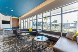 een woonkamer met banken, tafels en ramen bij Daytona 2BR w Parking – Family Pet Friendly in Daytona Beach