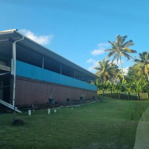 a building with palm trees in front of it at Mama MIREKA Homestay in Arorangi