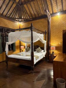 a bedroom with a canopy bed in a room at Lihat Sawah Cottage in Sidemen