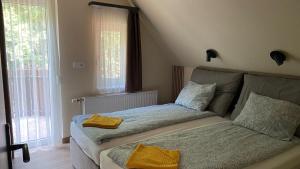a bedroom with two beds and two windows at Trio Relax Apartmanok in Kiskunmajsa