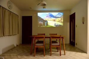 a dining room table with chairs and a tv on the wall at 仙台リバーサイドリトリート in Sendai