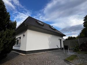 a white house with a black roof on a brick driveway at # 97 - die Ferienwohnung am Sachsenring in Oberlungwitz