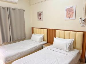 two beds in a room with white sheets at The Betong Life Guesthouse in Betong