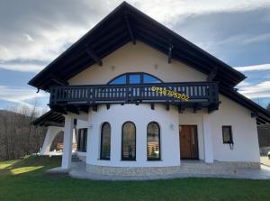 Una casa blanca con un balcón encima. en Julien House, en Prisaca Dornei