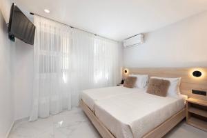 a white bedroom with a bed and a television at Evdokia Artheon in Rhodes Town