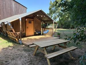 a wooden tent with a picnic table and a bench at Tente safari in Sainte-Soulle